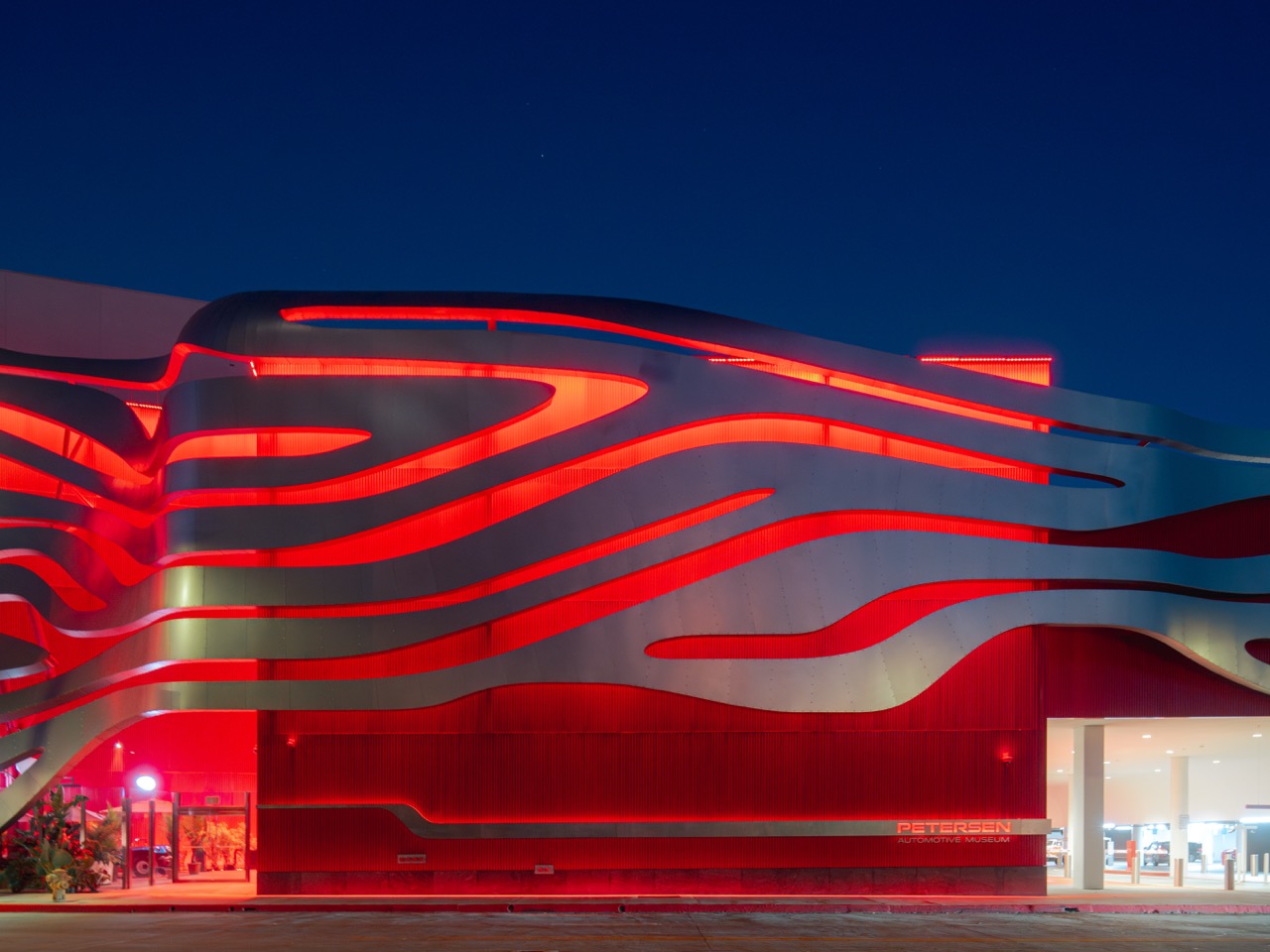 Ribboned museum facade lit red against a deep blue evening sky
